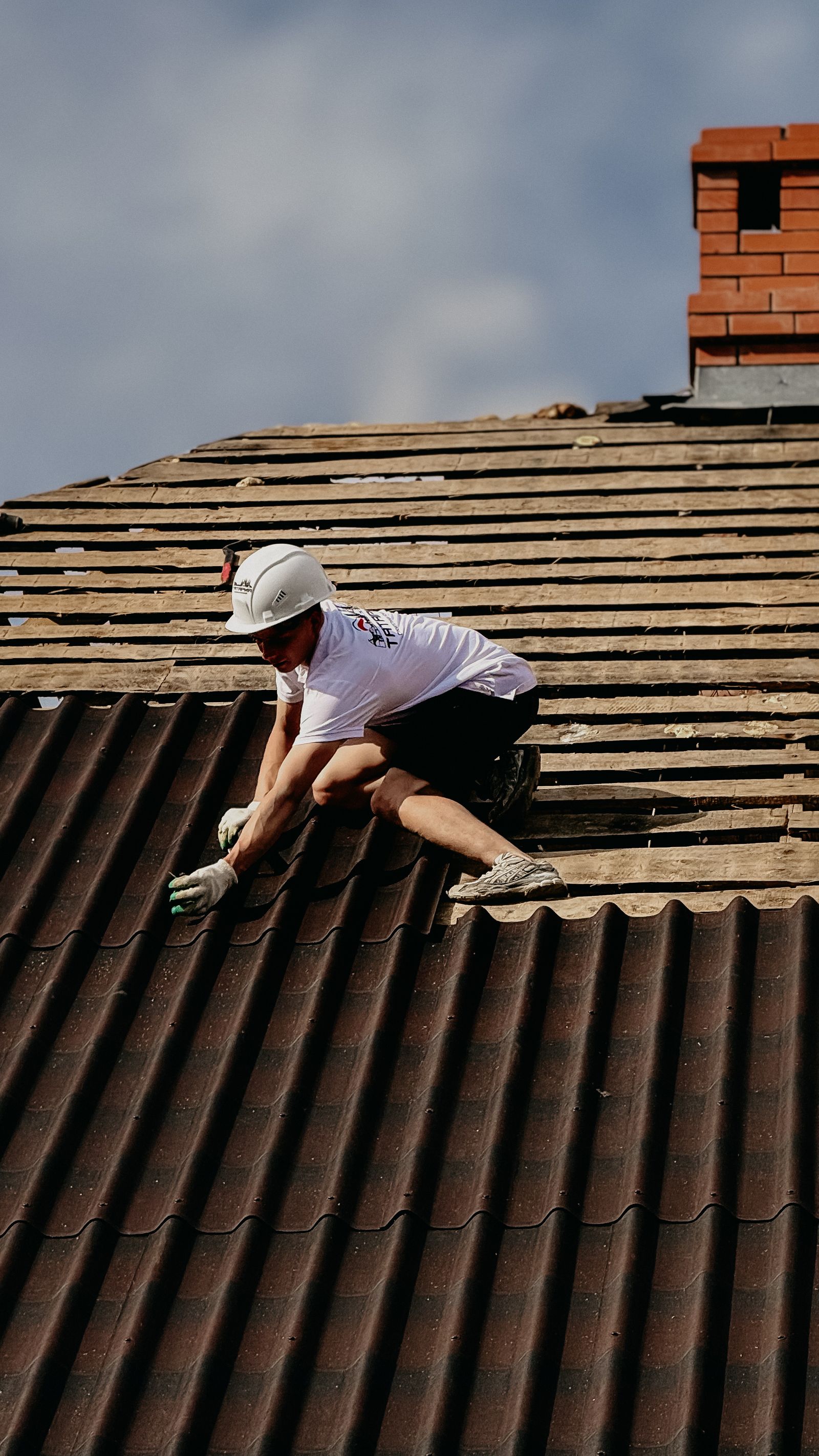 Professional roofer installing charcoal shingles on a suburban home